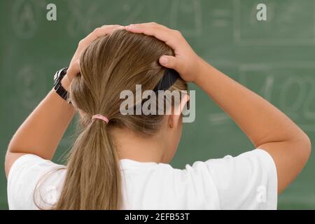 Rückansicht eines Schulmädchens mit ihren Händen in ihr Haare Stockfoto