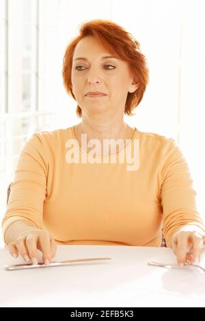 Nahaufnahme einer älteren Frau, die am Tisch sitzt und schaut Weg Stockfoto