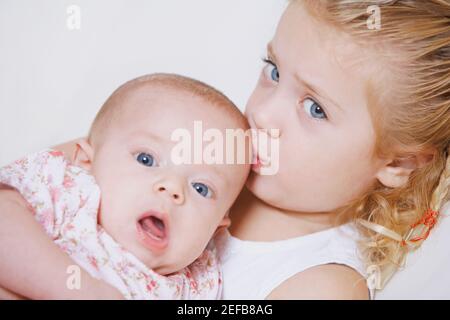 Porträt eines Mädchens, das ihren Bruder auf den Kopf küsst Stockfoto