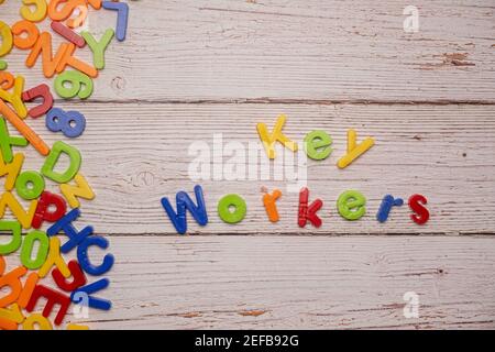 Bunte Magnetbriefe auf einem rustikalen weißen Tisch zu Hause Schule Coronavirus Rechtschreibung Key Workers Stockfoto