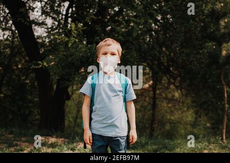 Kid boy in Maske mit blauem Rucksack unterwegs Stockfoto