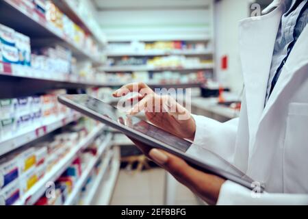 Nahaufnahme der Hände einer jungen Apothekerin, die den Bestand überprüft Medizinisches Geschäft mit digitalem Tablet Stockfoto