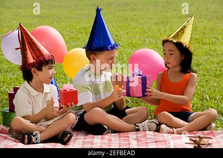 Drei Kinder sitzen zusammen auf einer Picknickdecke Stockfoto