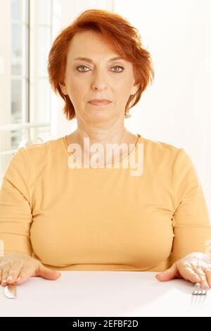 Porträt einer älteren Frau, die am Tisch sitzt Stockfoto