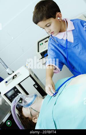 Junge imitiert einen Arzt und untersucht einen Patienten mit einem Stethoskop Stockfoto