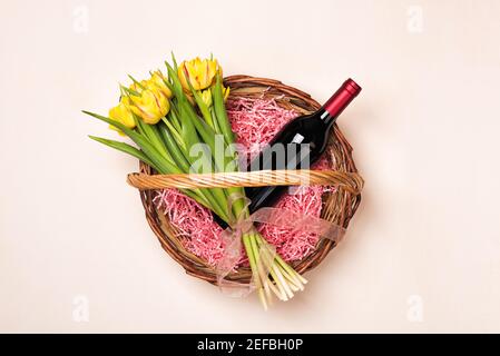 Flasche Rotwein und Tulpenblüten im Geschenkkorb Stockfoto