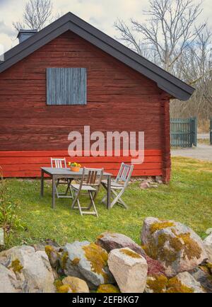 Rotes Gartenhaus mit Tisch und Stühlen, in ländlicher Umgebung. Stockfoto