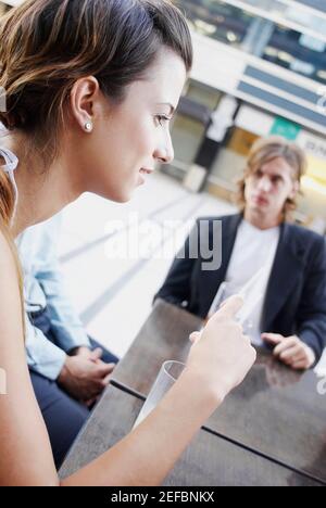 Seitenprofil einer jungen Frau mit sitzenden Freunden In einem Restaurant Stockfoto