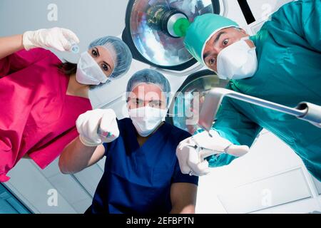 Low-Angle-Ansicht von zwei männlichen Chirurgen und einem weiblichen Chirurg hält chirurgische Geräte Stockfoto