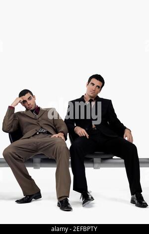 Zwei Geschäftsleute, die auf einer Bank sitzen und gestresst aussehen Stockfoto