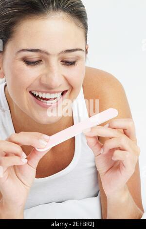 Nahaufnahme einer jungen Frau, die ihre Nägel feilte und lächelte Stockfoto