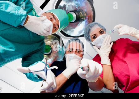 Low-Angle-Ansicht von zwei männlichen Chirurgen und einem weiblichen Chirurg sieht überrascht aus Stockfoto