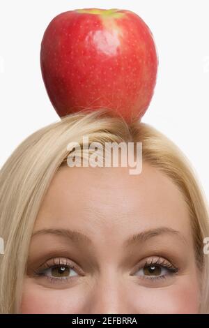 Porträt einer jungen Frau, die einen Apfel auf dem Kopf balancieren Stockfoto