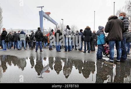 17. Februar 2021, Mecklenburg-Vorpommern, Warnemünde: Vor der Werft MV Werft in Warnemünde versammeln sich Mitarbeiter zu einer Protestkundgebung, die sich in einer Pfütze widerspiegelt. Die Werftarbeiter sind dem Aufruf der IG Metall gefolgt, die ihren Forderungen nach den Werften MV Gewicht verleiht, die mit Arbeitsplatzabbau bedroht sind. Sie fordert, dass die Bundesregierung so schnell wie möglich Geld aus dem Fonds für wirtschaftliche Stabilisierung zur Verfügung stellt und die Kurzzeitarbeitsregelung verlängert. Foto: Bernd Wüstneck/dpa-Zentralbild/dpa Stockfoto