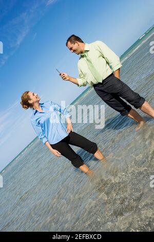 Mittlerer Erwachsener, der ein Foto eines mittleren Erwachsenen fotografiert Frau am Strand Stockfoto