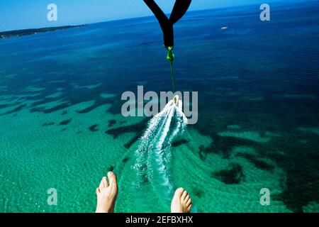 A mans Füße werden gesehen, wie er über Negril Beach, Jamaika parasail Stockfoto