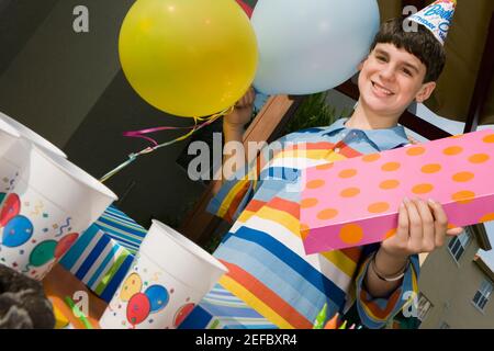 Porträt eines Jungen mit einem Geburtstagsgeschenk und Ballons Stockfoto