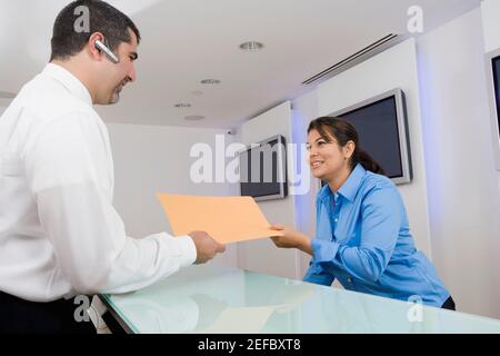 Geschäftsmann, der einer Geschäftsfrau eine Akte gibt Stockfoto