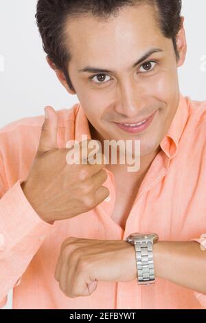 Portrait eines jungen Mannes, der nach der Überprüfung Daumen nach oben gibt Die Zeit auf seiner Armbanduhr Stockfoto