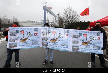 17. Februar 2021, Mecklenburg-Vorpommern, Warnemünde: Vor der Werft MV Werft in Warnemünde versammeln sich Mitarbeiter zu einer Protestkundgebung; auf einem Transparent steht unter anderem: "Alles im selben Boot! Die Werftarbeiter sind dem Aufruf der IG Metall gefolgt, die ihre Forderungen an die mit Arbeitsplatzabbau bedrohten MV-Werften betont. Sie fordern, dass die Bundesregierung Geld aus dem Fonds zur wirtschaftlichen Stabilisierung So bald wie möglich und eine Verlängerung der Kurzzeitarbeitsverordnung zur Verfügung stellt. Foto: Bernd Wüstneck/dpa-Zentralbild/dpa Stockfoto