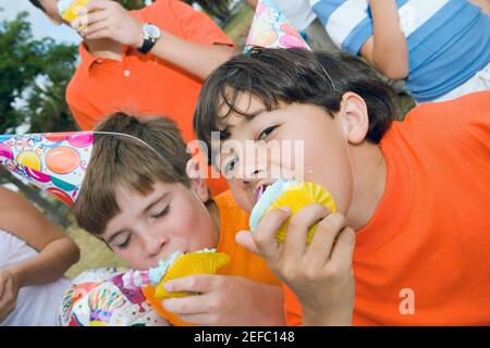 Portrait von zwei Jungen, die Cupcakes essen Stockfoto