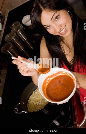 Porträt einer jungen Frau, die eine Tomatenschüssel hält Suppe in der Küche Stockfoto