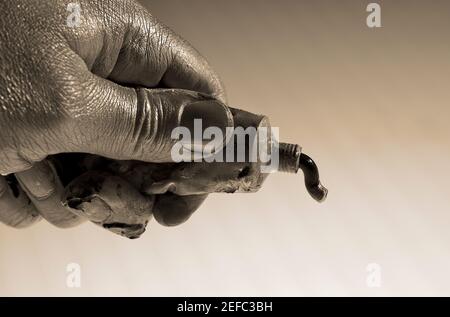 Nahaufnahme einer personÅ½s Hand, die ein Farbrohr zusammendrückt Stockfoto