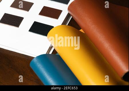 Leder-Musterbuch mit verschiedenen Farben und 3pieces Ledermuster (blau, gelb, braun) auf Holztisch. Stockfoto