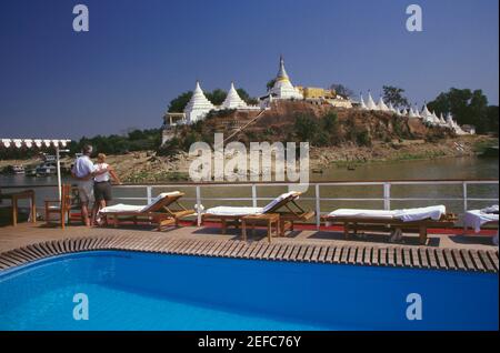 Rückansicht eines Paares, das auf einem Kreuzfahrtschiff steht und eine Pagode anschaut, Shwe Kyet Pagode, Mandalay, Myanmar Stockfoto