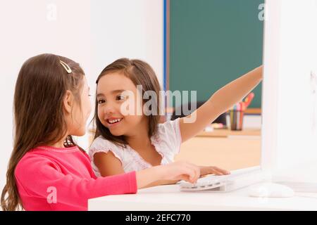 Seitenprofil von zwei Schülerinnen lächeln vor einem Computer Stockfoto