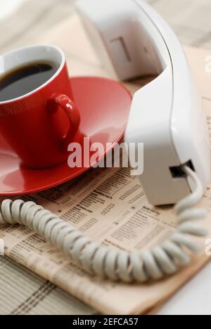 Nahaufnahme einer Tasse schwarzen Tee mit einem Telefon Empfänger in einer Zeitung Stockfoto