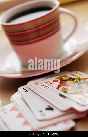 Nahaufnahme einer Tasse schwarzen Tee mit Spielkarten Stockfoto