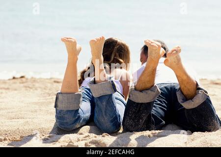 Rückansicht eines mittelerwachsenen Mannes und eines Jungen Frau liegt am Strand Stockfoto