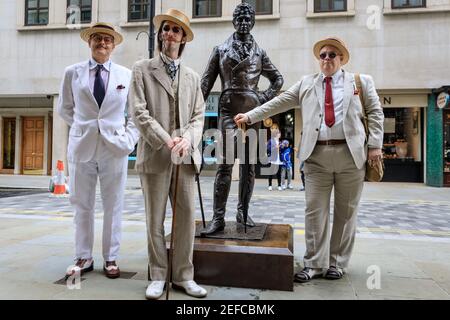 Dapper British Chaps mit der Statue von Beau Brummell auf dem 'Grand Flaneur' CHAP Walk, Mayfair, London, Großbritannien Stockfoto