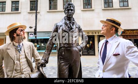 Dapper British Chaps mit der Statue von Beau Brummell auf dem 'Grand Flaneur' CHAP Walk, Mayfair, London, Großbritannien Stockfoto