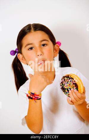 Portrait eines Mädchens, das einen Donut hält und sie leckt Finger Stockfoto