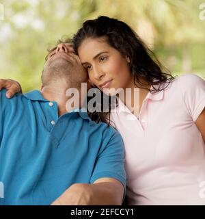 Nahaufnahme einer jungen Frau, die neben einer Schlafmitte sitzt Erwachsener Mann Stockfoto