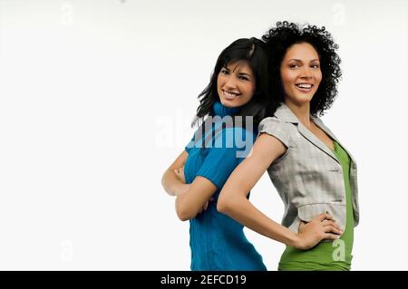 Seitenprofil von zwei jungen Frauen, die Rücken an Rücken stehen Und lächelnd Stockfoto
