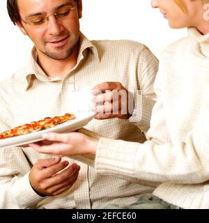 Geschäftsfrau, die einem Geschäftsmann Pizza anbietet Stockfoto