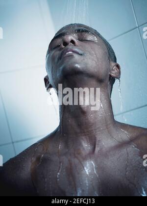 Nahaufnahme eines Mannes mit mittlerem Erwachsenen, der eine Dusche nimmt Das Badezimmer Stockfoto