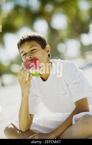 Porträt eines Jungen im Teenageralter, der ein Stück Wassermelone isst Stockfoto