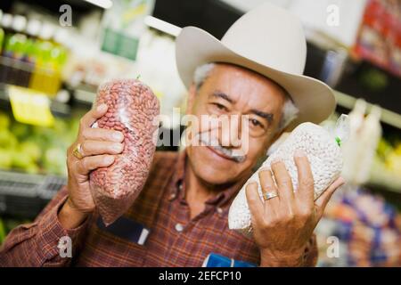 Porträt eines älteren Mannes, der Pakete in einem Supermarkt hält Stockfoto