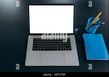 Nahaufnahme eines Arbeitsplatzes, eines Laptops mit leerem weißen Bildschirm, eines Notizblocks und eines Briefpapiers. Speicherplatz kopieren Stockfoto