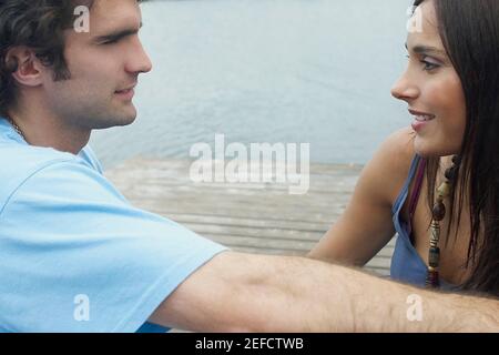 Nahaufnahme eines jungen Paares, das an einem Pier und sitzt Einander anschauend Stockfoto