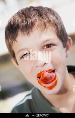 Portrait eines Jungen, der Ketchup von seinen Lippen leckt Stockfoto