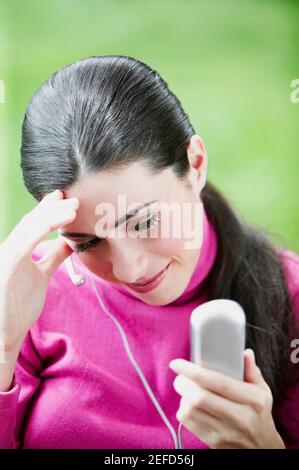 Nahaufnahme einer jungen Frau mit Mobiltelefon und Grinst Stockfoto