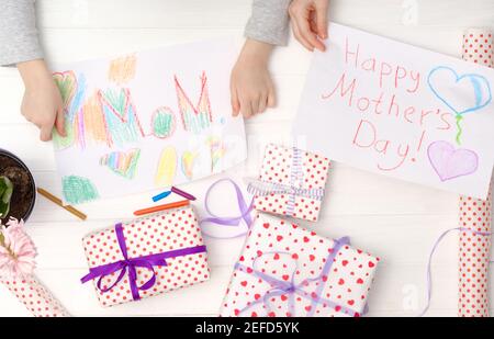 Happy Mother's Day Karte von kleinen Kind gemacht. Mädchen Hände halten eine handgemachte Karten mit geschenkkartons. Stockfoto