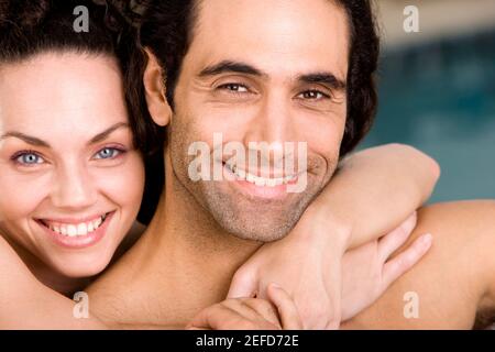 Porträt einer jungen Frau, die einen Mitte erwachsenen Mann von hinten umarmen Stockfoto