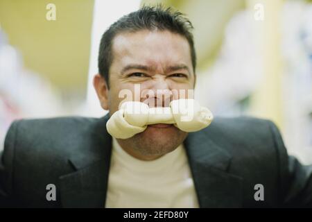Porträt eines mittleren erwachsenen Mannes mit einem Hundeknochen In seinem Mund