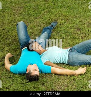 Erhöhte Ansicht eines jungen Paares liegen auf dem Rasen Stockfoto